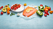 Salmon fillet with lemon slices and fresh vegetables on a light blue background