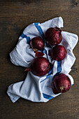 Whole red onions on a rustic tea towel