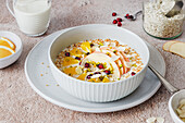 Porridge with apple slices, orange, pomegranate seeds and almonds