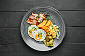 Fried egg with roasted ham, potato wedges, pickled cucumber and coleslaw