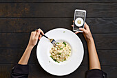 Woman checks the calories and ingredients of a risotto with her smartphone