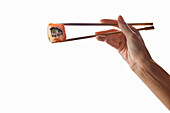 Woman's hand holding salmon maki with chopsticks