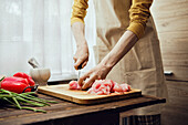 Man slices raw chicken breast on wooden board