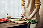 Man slices spring onions on a wooden board