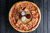 Pizza with slices of sausage and three different dips