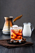 Iced coffee with ice cubes and chocolate-coated almonds