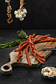 Homemade kabanossi on a wooden board with garlic