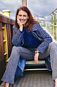 Rothaarige Frau in blau-karierter Jacke und Jeans