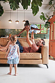 Father playing with daughters on sofa