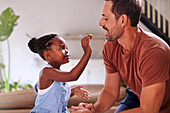 Girl feeding father with cake at home