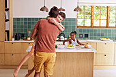 Father carrying son in kitchen