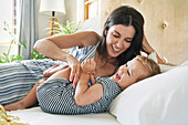 Mother playing with daughter on bed