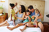 Parents with children relaxing on bed