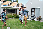 Parents with children playing in backyard