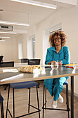 Smiling woman sitting at table in modern creative studio