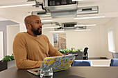 Smiling man with laptop in modern office