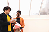 Smiling creative workers looking at notepad in studio