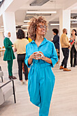 Employee holding coffee and smiling during meeting