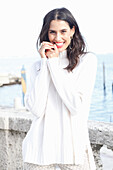 Long-haired young woman in white turtleneck jumper, laughing, red lipstick