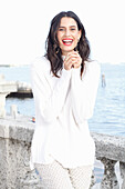 Long-haired young woman in white turtleneck jumper, laughing, red lipstick