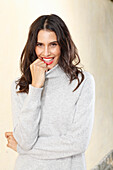 Long-haired young woman in white turtleneck jumper, laughing, red lipstick