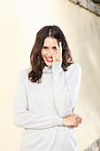 Long-haired young woman in white turtleneck jumper, laughing, red lipstick