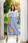 Woman in blue skirt with buttons and white T-shirt with lettering