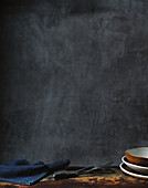 Rustic table with crockery and cutlery against a dark grey background