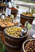 Different types of pickled olives in wooden barrels