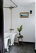 Free-standing bathtub with golden tap on a dark terrazzo floor