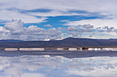 Salt mining operations on the salt flats of Salinas Grandes in northwest Argentina. Clouds are reflected on a shallow sheet of water.