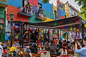 Tourists eat al fresco in a sidewalk cafe and watch tango dancers in Caminito, La Boca, Buenos Aires, Argentina.