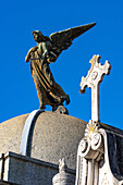 A cross & an angel statue on an elaborate tomb or mausoleum in the Recoleta Cemetery, Buenos Aires, Argentina.