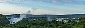 Iguazu National Park at sunrise with a plume of mist rising from the Devil's Throat. The complex of falls extends for 2.7 kilometers with the border between Brazil and Argentina passing through the Devil's Throat. A UNESCO World Heritage Site.