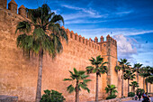 Rabat, Morocco, Apr 24 2015, The impressive walls of the Kasbah of the Udayas stand tall in Rabat, Morocco, adorned with palm trees under a vibrant sunset sky.