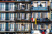 Vibrant facade of Porto apartments with traditional tiles, laundry hanging outside, capturing daily life and Portuguese architecture.