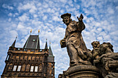 Statue des Heiligen Ivo von Kermartin und alter Turm an der Karlsbrücke in Prag