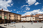 Visitors enjoy the historic Plaza Mayor in Berlanga de Duero, surrounded by charming architecture and a striking blue sky.