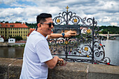 Tourists touching a plaque in Charles Bridge for good luck, Prague.