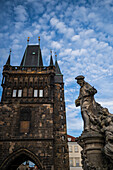 Statue des Heiligen Ivo von Kermartin und alter Turm an der Karlsbrücke in Prag