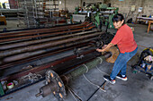 A machine to wind yarn onto the very large bobbin by the worker at Hilandería Warmi, a weaving mill in Palpalá, Argentina. The powerloom weaving machines use these large bobbins for the base-color yarn.