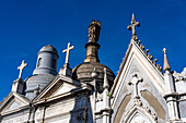 Crosses & a statue on elaborate tombs or mausoleums in the Recoleta Cemetery, Buenos Aires, Argentina.