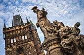 Statue des Heiligen Ivo von Kermartin und alter Turm an der Karlsbrücke in Prag