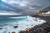 A stunning long exposure shot of the Garachico coast in northern Tenerife, Canary Islands, Spain with dramatic clouds and crashing waves.