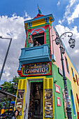 Ein Tourist posiert für ein Foto an der Kreuzung der Straßen Caminito und Magallanes in La Boca, Buenos Aires, Argentinien