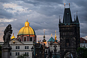 View of St. Francis of Assisi Church and city skyline at sunset from Charles Bridge in Prague