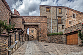 The stunning stone arch of Puerta del Rio welcomes visitors to the charming village of Yanguas in the region of Soria, surrounded by rustic buildings.