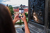 Tourists touching a plaque that is part of the statue St. John of Nepomuk for good luck, Prague.