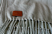 The leather Warmi tag on a woven shawl at Hilandería Warmi, a weaving mill in Palpalá, Argentina.