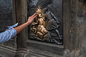 Tourists touching a plaque that is part of the statue St. John of Nepomuk for good luck, Prague.